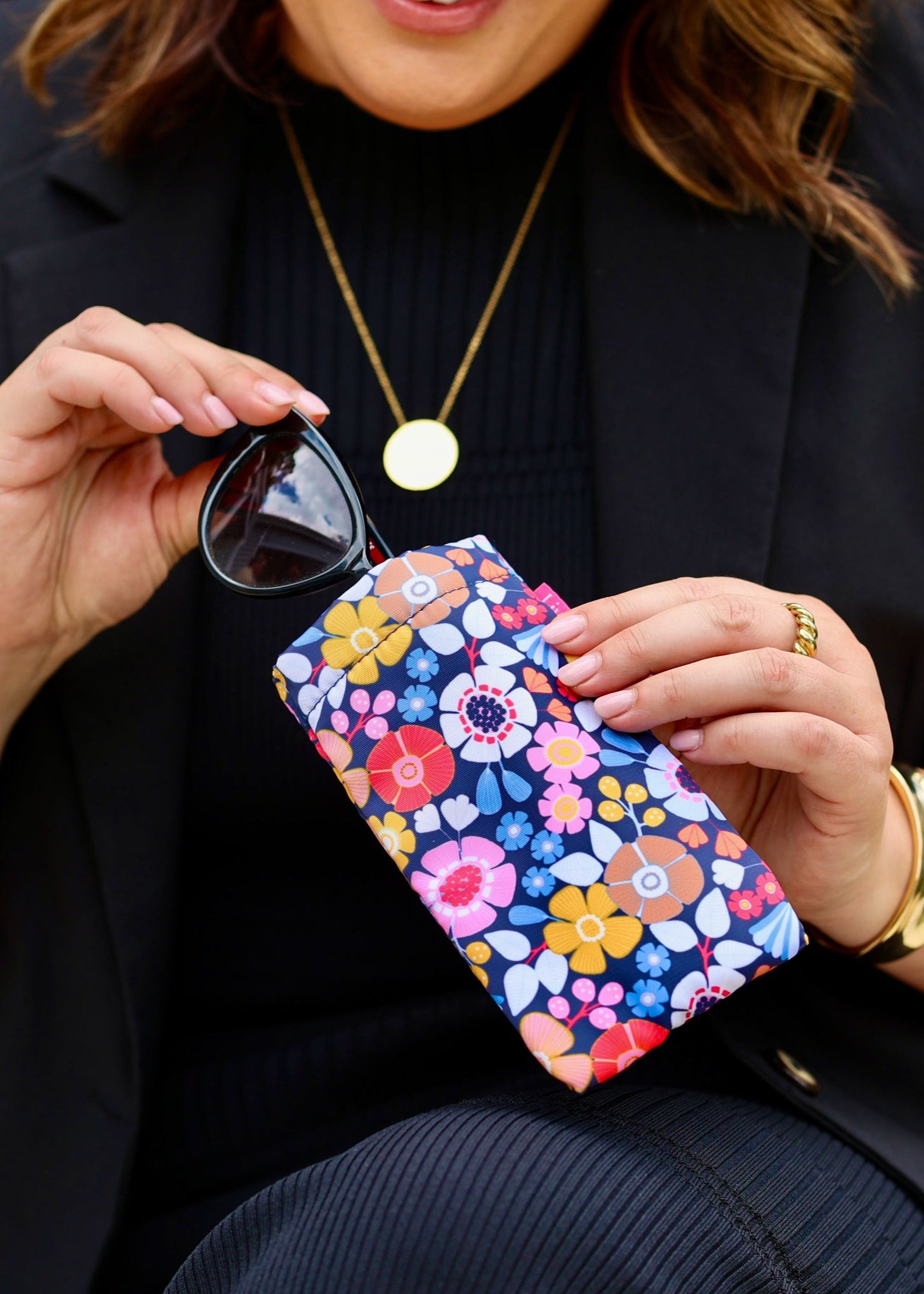 A person holding glasses in a floral patterned case.