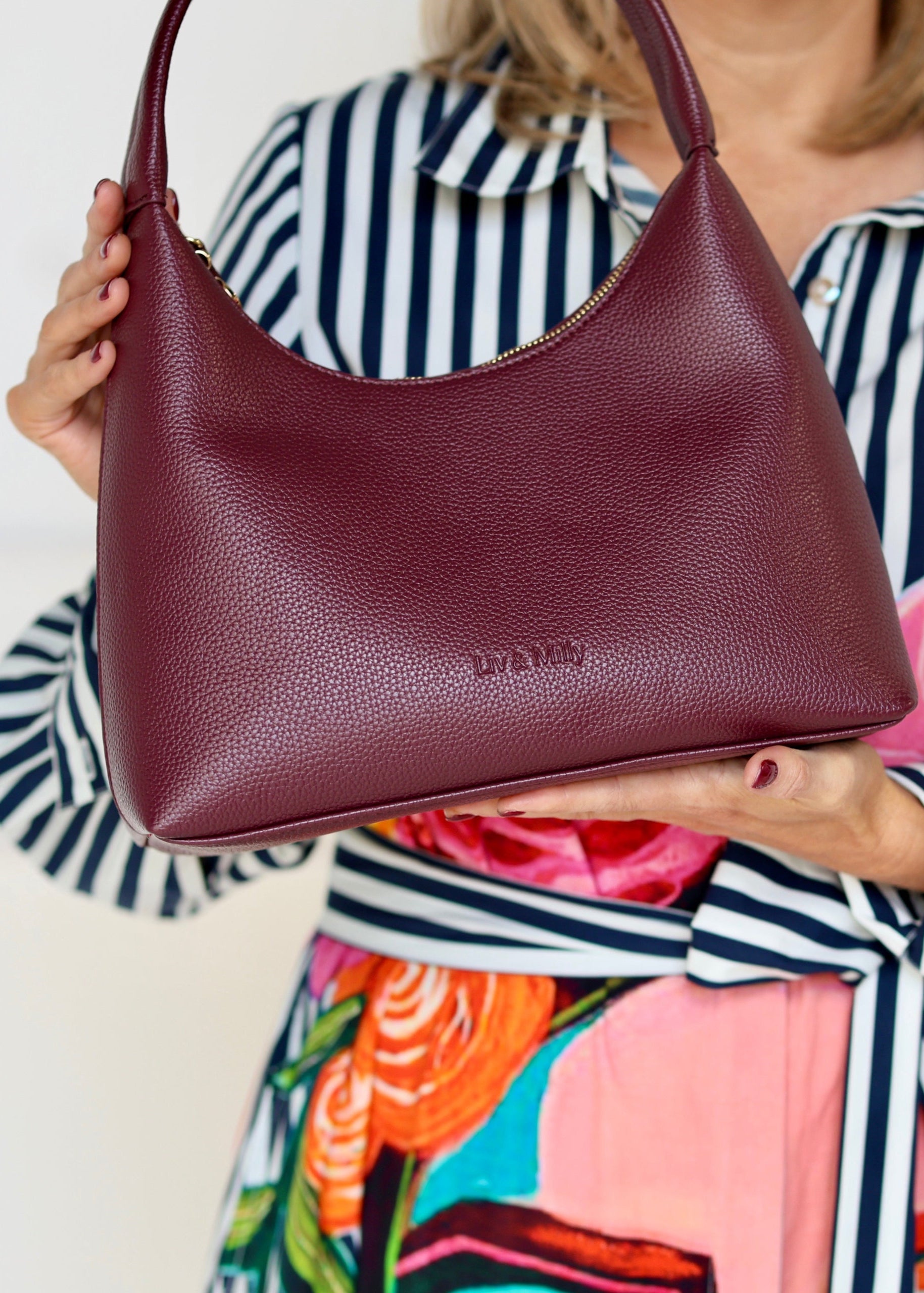 Person holding a maroon handbag with a colorful shirt underneath