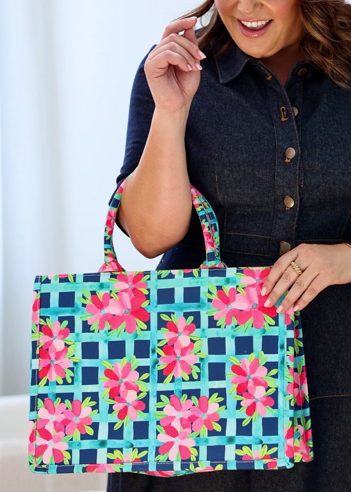 A person holding a multicolored floral book bag.